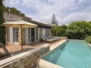 a swimming pool with an umbrella next to a house at Belvilla by OYO Blu Marine in Font de Sa Cala