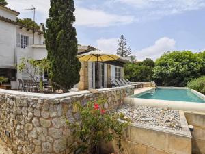 a house with a swimming pool and a stone wall at Belvilla by OYO Blu Marine in Font de Sa Cala