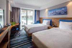 a hotel room with two beds and a desk and a television at Hampton by Hilton Istanbul Kurtkoy in Istanbul