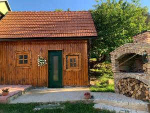 Cabaña de madera pequeña con puerta verde y piedra horno en Ivona - Kuća za odmor Perušić - Stara Lika, en Perušić