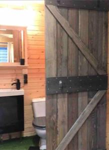 uma porta de madeira numa casa de banho com WC em Tiny House Close to Brussels South Charleroi Airport em Courcelles