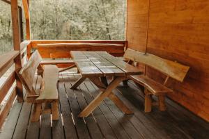 una mesa de madera y sillas en el porche de una cabaña en Domek na skarpie, en Joniec