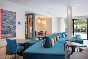 a waiting room with blue chairs and tables at Hampton By Hilton Kaiserslautern in Kaiserslautern