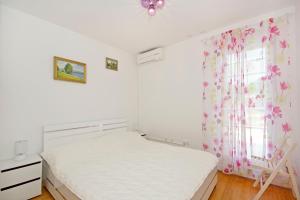 a white bedroom with a bed and a window at Tatiana Penthouse in Podstrana