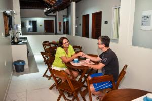 mężczyzna i kobieta siedzący przy stole w obiekcie RECANTO PRAIA SUITES w mieście Arraial do Cabo