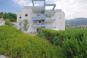 a white building on a hill with green bushes at Tatiana Penthouse in Podstrana