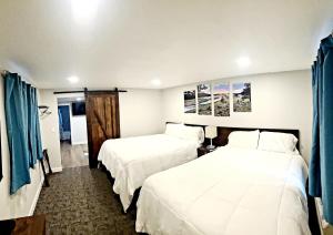 two beds in a hotel room with blue curtains at Snowy Mountain Inn in Saratoga