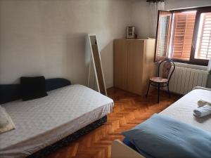 a room with two beds and a chair in it at Apartment Zdenka 1 in Trogir