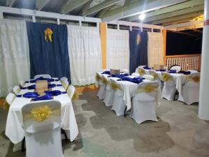 a row of tables in a room with white chairs at Chaleanor Hotel in Dangriga