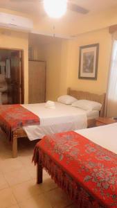 Habitación de hotel con 2 camas con asientos rojos en Chaleanor Hotel en Dangriga