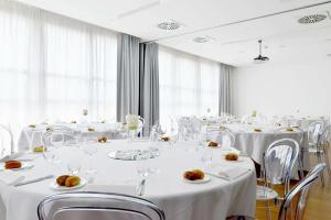 une salle de conférence avec des tables et des chaises blanches dans l'établissement Hilton Garden Inn Milan North, à Milan