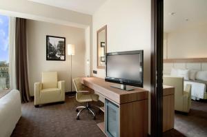 ミラノにあるダブルツリー バイ ヒルトン ミランのデスク、テレビ、ベッドが備わるホテルルームです。