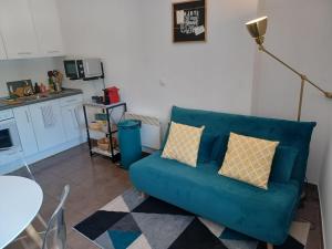 a blue couch in a living room with a kitchen at Le Peyragudes - Rue de la Grotte - 36m in Lourdes