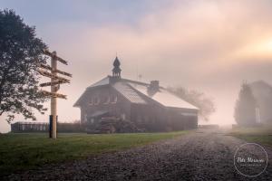 an old barn on a foggy field with a church at Hájenka Knížecí Pláně in Borová Lada