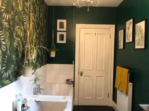 La salle de bains est pourvue d'une baignoire blanche et de murs verts. dans l'établissement Hetherington House, à Maybole
