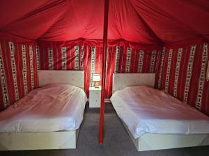 two beds in a room with a red tent at Mango Farm Camp in Al-Disah