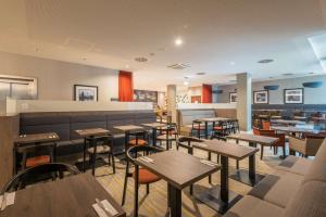 a restaurant with wooden tables and chairs and a cafeteria at Hampton By Hilton Munich City West in Munich