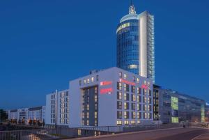 un gran edificio con un rascacielos alto en el fondo en Hilton Garden Inn Munich City West en Múnich