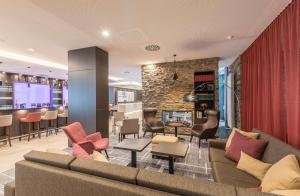 a lobby with a couch and chairs and a bar at Hilton Garden Inn Munich City West in Munich
