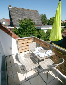 un patio con mesa, sillas y sombrilla en Ferienwohnung Muschelweg 9b Ostermann, en Norddeich