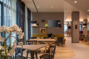 a dining room with tables and chairs and windows at Hampton By Hilton Munich City North in Munich