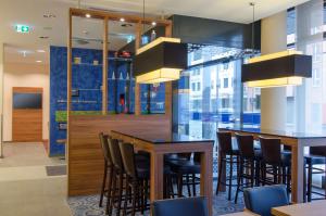 a restaurant with a bar with chairs and tables at Hampton by Hilton Nürnberg City Center in Nuremberg