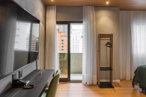 a room with a desk and a bed and a window at Cyclinn Jesuíno Arruda Itaim in São Paulo
