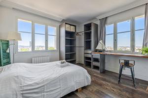 a bedroom with a bed and a desk and windows at Beautiful 2-room apartment with a view in Lyon - Welkeys in Lyon