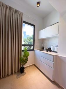 a kitchen with white cabinets and a large window at White Door Apartments in Haifa