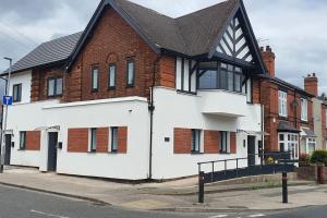 a white house with a black roof on a street at Glamour no2 Flat in Mansfield