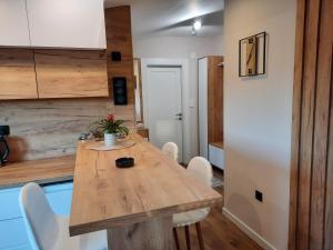 cocina con mesa de madera y sillas blancas en Dream Home Nis, en Niš
