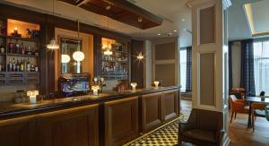 a bar in a restaurant with a table and chairs at Reykjavik Konsulat Hotel, Curio Collection By Hilton in Reykjav&iacute;k