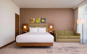 1 dormitorio con 1 cama blanca grande y 1 sofá en Hilton Garden Inn Orenburg en Oremburgo