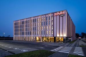 a building with a sign on the side of it at Hampton by Hilton Riga Airport in Rīga