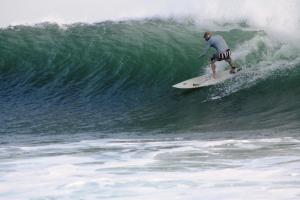 un hombre montando una ola en una tabla de surf en el océano en Punta Roca Surf Resort en La Libertad