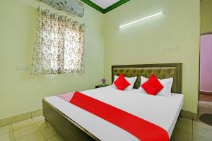 a bedroom with a bed with red and white pillows at Flagship B N Palace in Raipur