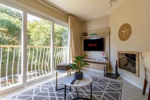 a living room with a large window and a tv at Bem localizado - @stayhousetemporada in Canela