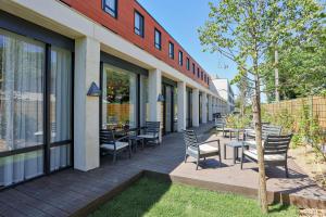 a patio with chairs and tables outside of a building at Hampton By Hilton Toulouse Airport in Blagnac