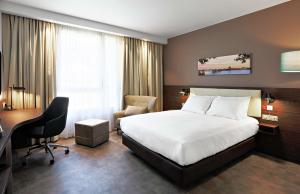a hotel room with a bed and a desk at Hampton By Hilton Toulouse Airport in Blagnac
