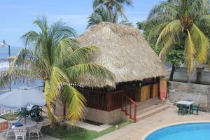 a hut with a swimming pool next to a resort at Punta Roca Surf Resort in La Libertad