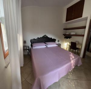 a bedroom with a bed with a purple comforter at B&B Easy Wind in Cala Gonone