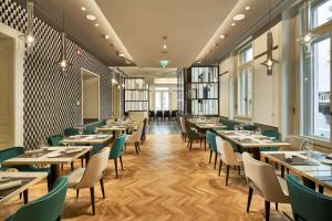 a restaurant with wooden tables and green chairs at DoubleTree By Hilton Trieste in Trieste