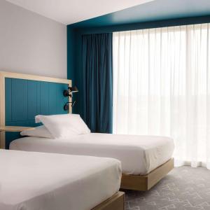 Cette chambre comprend 2 lits dans une chambre dotée de murs bleus et d'une fenêtre. dans l'établissement Hampton by Hilton Tours Centre, France, à Tours