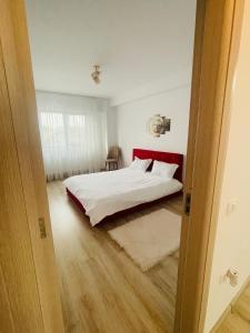 a bedroom with a bed with a red headboard at Apartament YRA Rm.Valcea in Râmnicu Vâlcea +1 photo