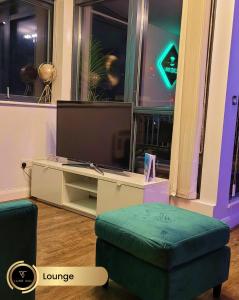 a living room with a tv and a green ottoman at Bull's Ring 3Bed Penthouse City Centre in Birmingham