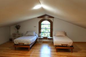 a attic room with two beds and a window at Casa AsCampinas in Ourense
