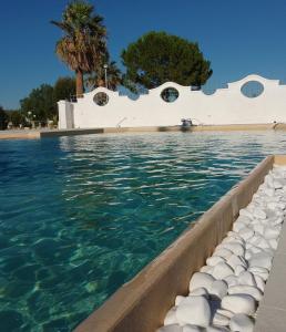 une piscine d'eau bleue et un bâtiment blanc dans l'établissement Casal Duca, à Tarente