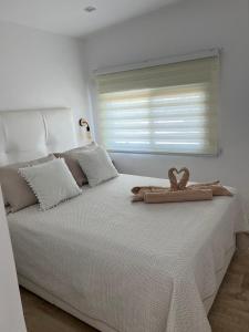 um quarto branco com uma cama com uma toalha em La Noria32 em Nerja