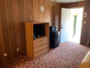 Cette chambre dispose d'une télévision et d'une commode avec un écran de visualisation. dans l'établissement El Portal Motel, à Beatty