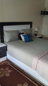 een bed met kussens in een slaapkamer bij شقة مفروشة للكراء اليومي في الناظور ليلى in Selouane